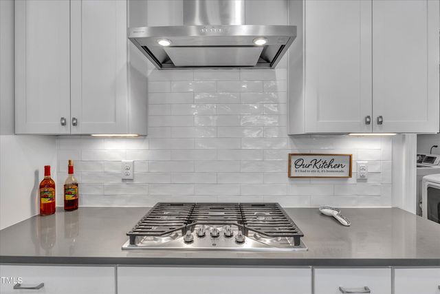 a kitchen with stainless steel appliances kitchen island a table chairs and a refrigerator