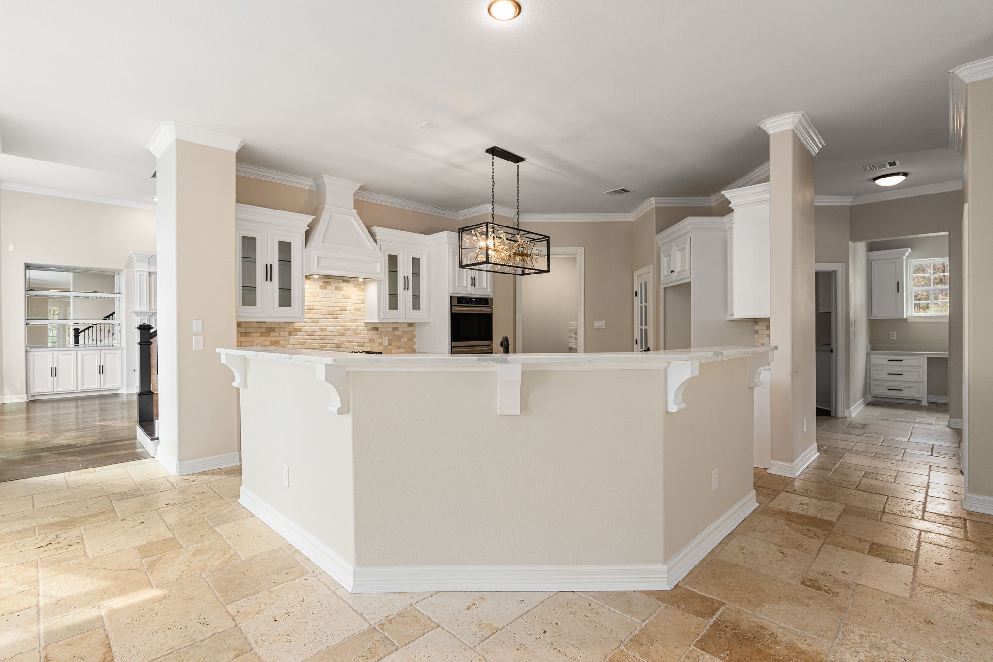 14882 Gingham Road Montgomery, TX 77356 - Photo 14 of 41 This photo showcases a spacious, bright kitchen with a central island, elegant white cabinetry, and a modern light fixture. The kitchen features a neutral color palette, brick backsplash, and ample storage, creating a warm and inviting atmosphere.