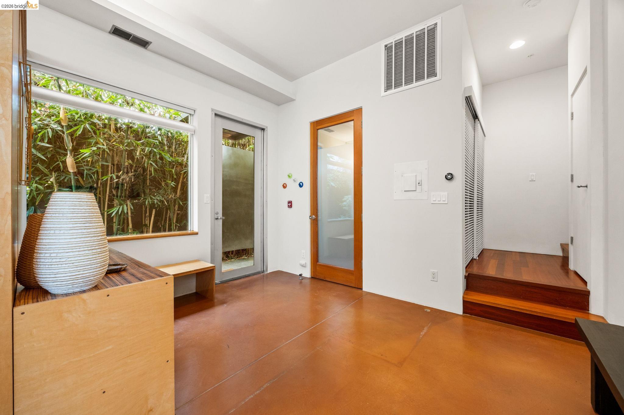 Polished concrete flooring, large pane window, wood-frame glass door, and rich wood stairs
