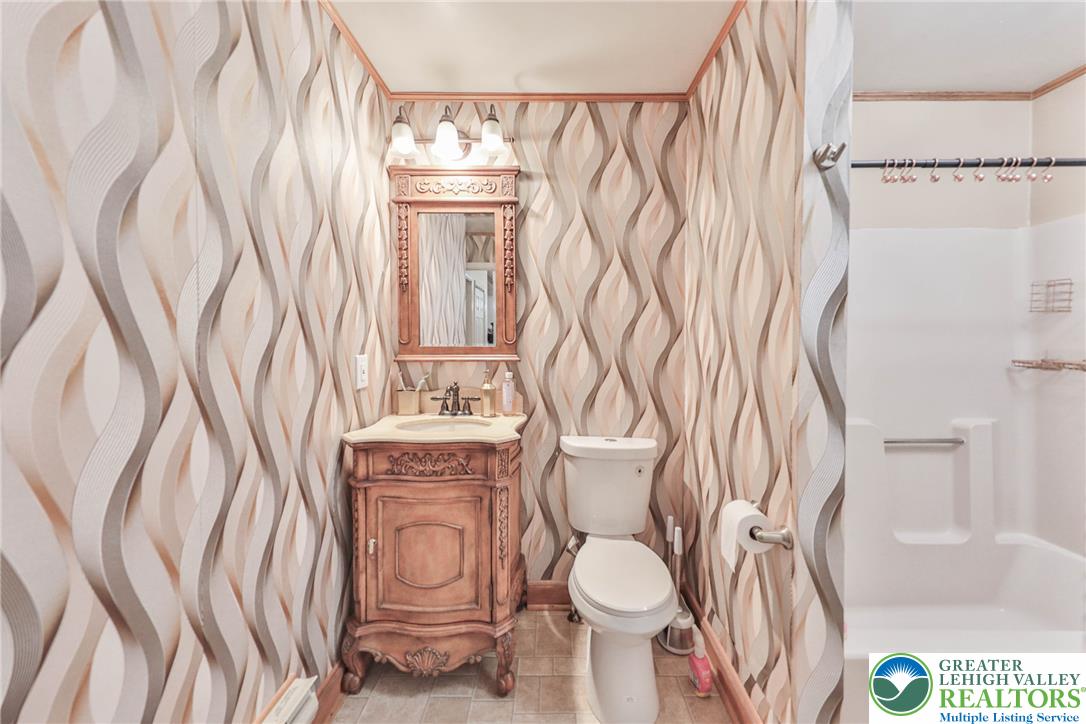 2114 Lakeview Road Bushkill, PA 18324 - Photo 23 of 83 Patterned walls surround a classic wood vanity and integrated tub shower unit.