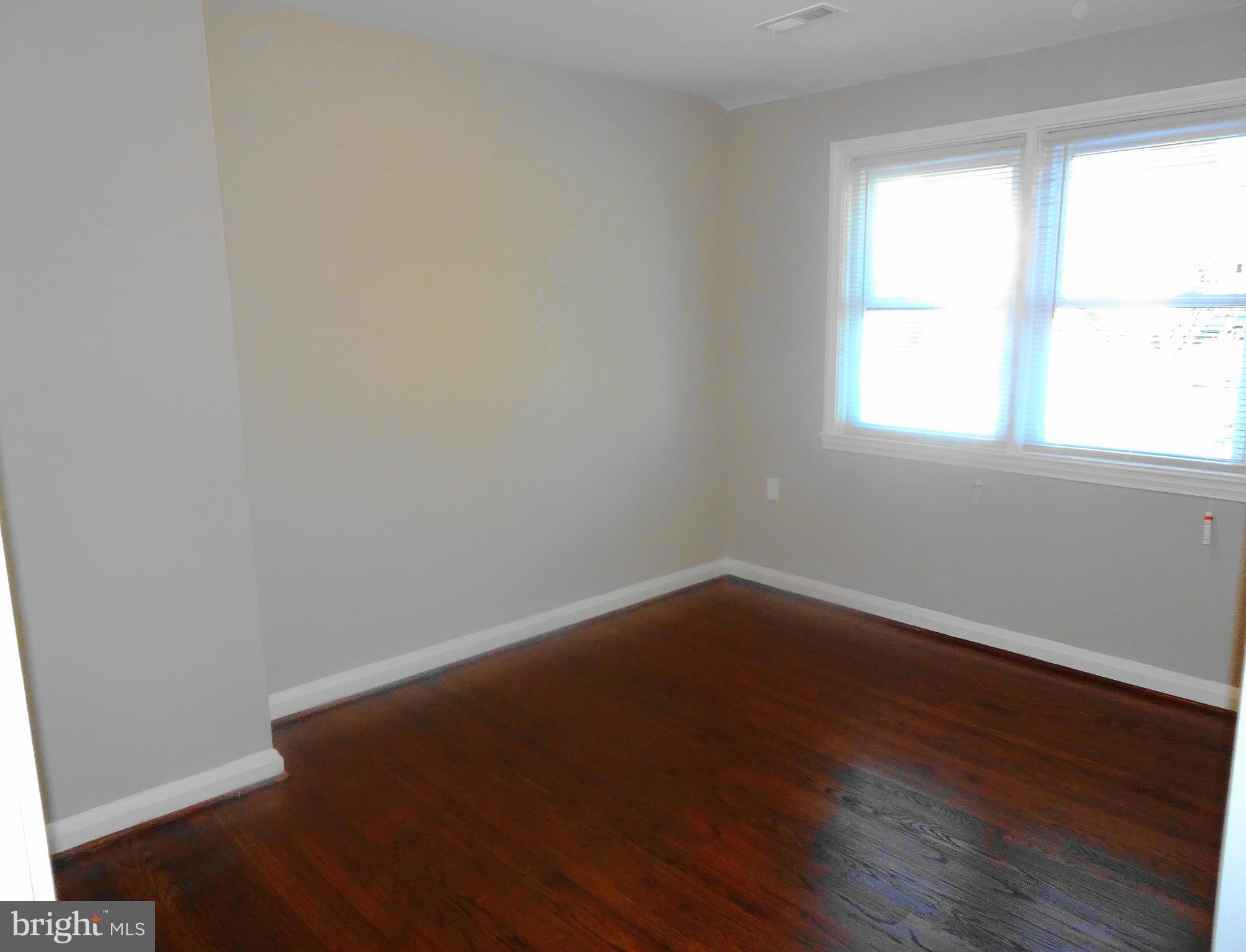 1406 Meridene Drive Baltimore, MD 21239 - Photo 15 of 30 an empty room with wooden floor and windows