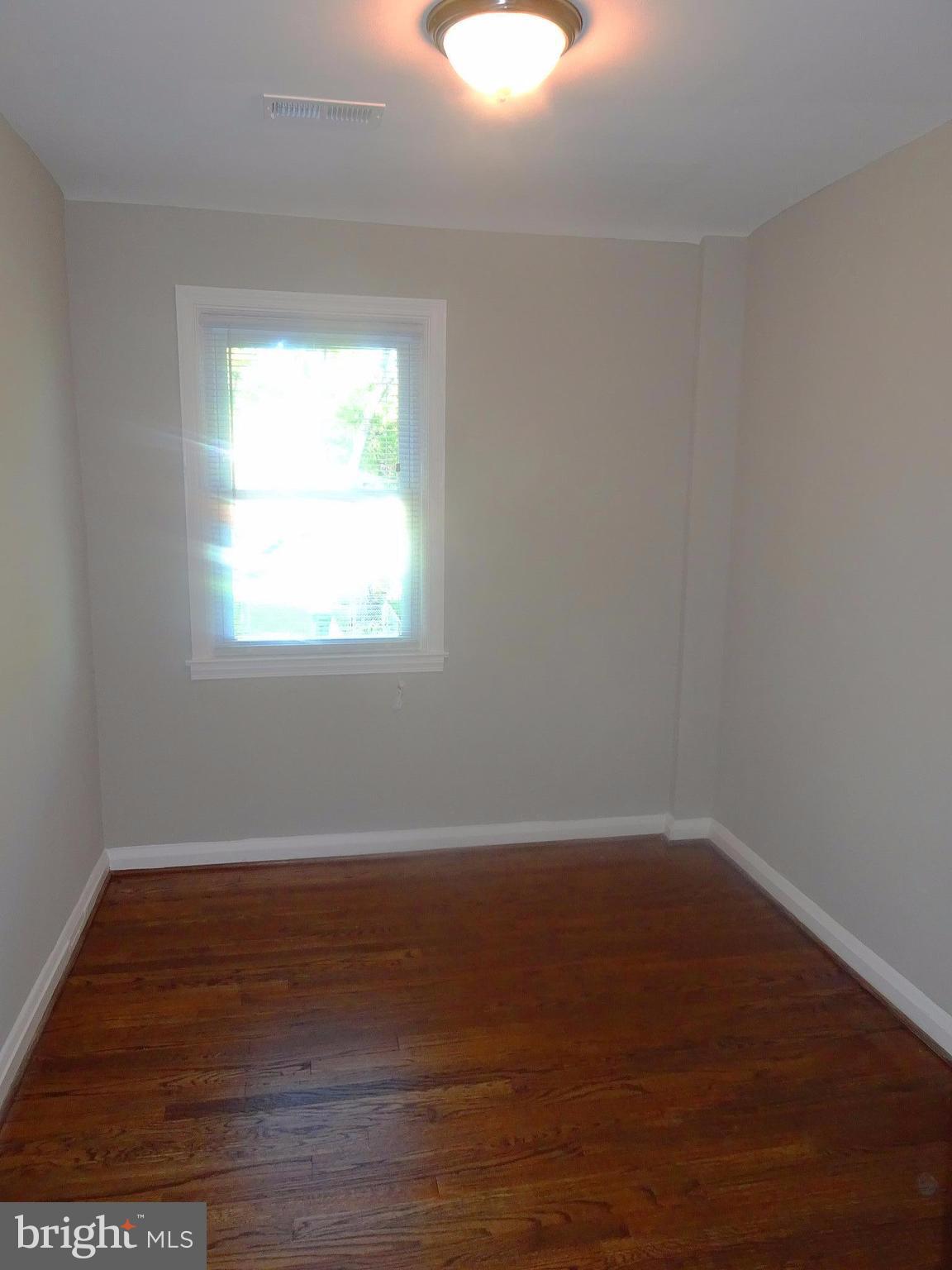 1406 Meridene Drive Baltimore, MD 21239 - Photo 16 of 30 an empty room with wooden floor and windows
