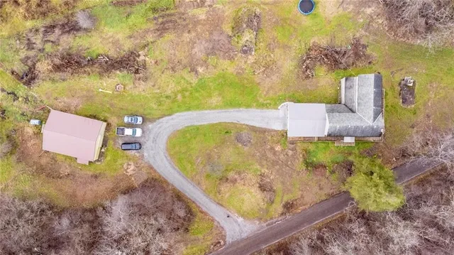 view of a wooden house with a yard and large trees