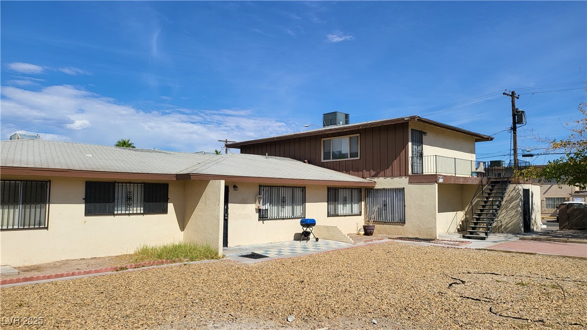 Rear view of house featuring stairs, stucco siding, and a patio
