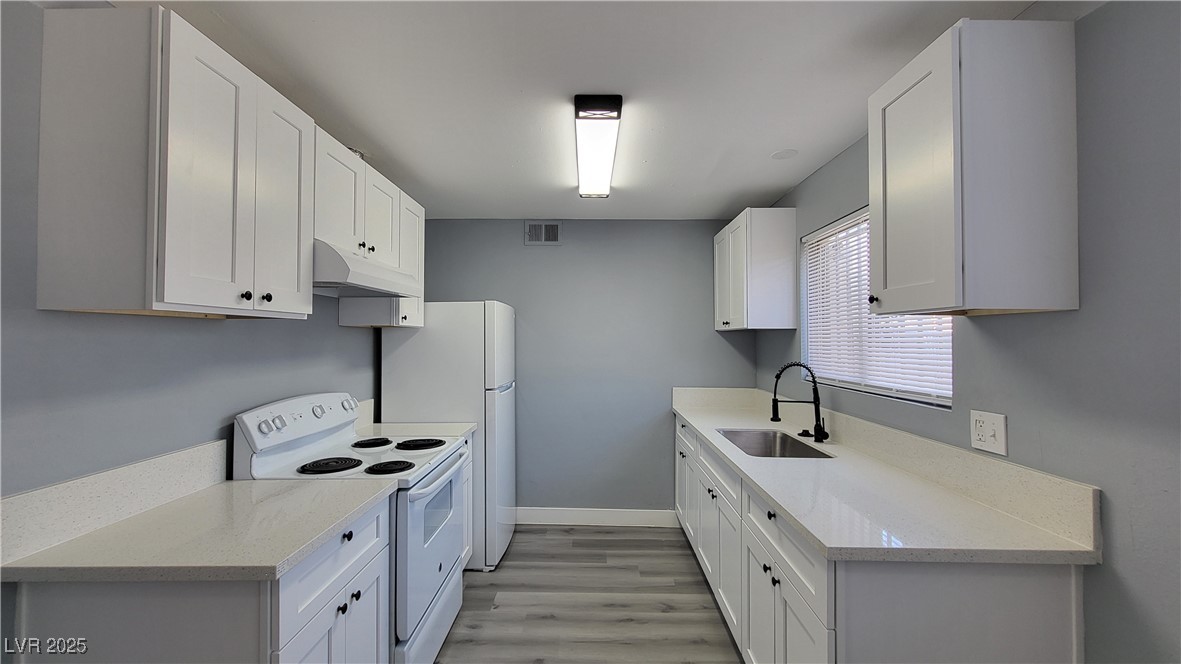 3240 Michael Way, Unit 3 Las Vegas, NV 89108 - Photo 12 of 22 Kitchen featuring white electric stove, light stone counters, light wood-type flooring, under cabinet range hood, and white cabinets