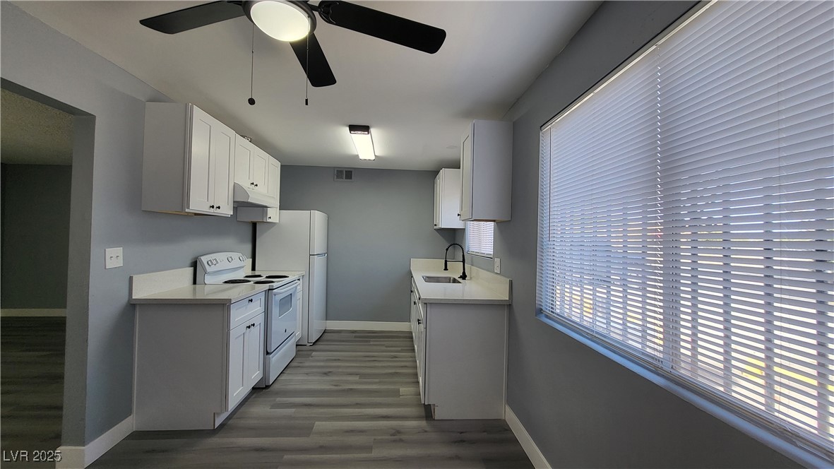 3240 Michael Way, Unit 3 Las Vegas, NV 89108 - Photo 14 of 22 Kitchen with white electric stove, light wood-style floors, white cabinets, and under cabinet range hood