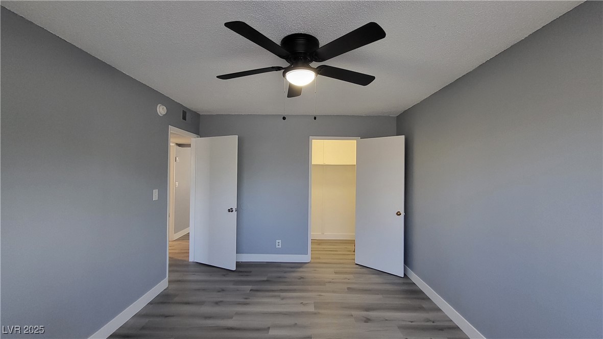 3240 Michael Way, Unit 3 Las Vegas, NV 89108 - Photo 15 of 22 Unfurnished bedroom with wood finished floors, a spacious closet, ceiling fan, and a textured ceiling
