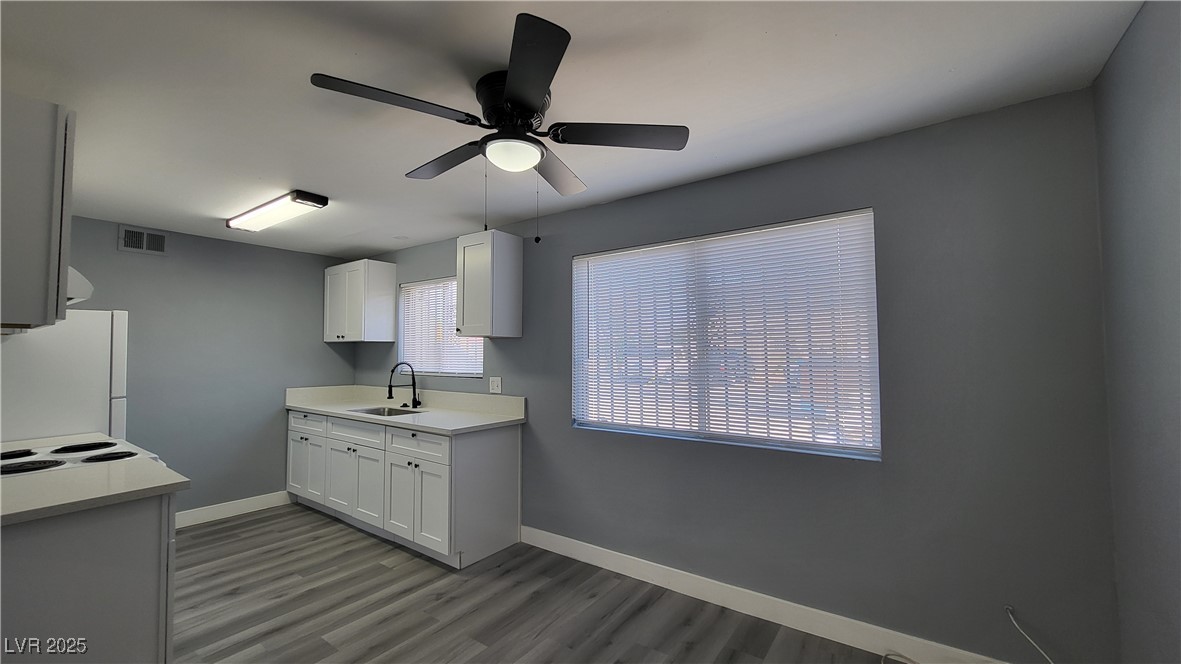 3240 Michael Way, Unit 3 Las Vegas, NV 89108 - Photo 9 of 22 Kitchen with light countertops, white cabinetry, ceiling fan, freestanding refrigerator, and dark wood finished floors