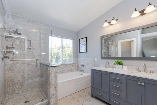 a bathroom with a granite countertop bathtub a sink and a shower