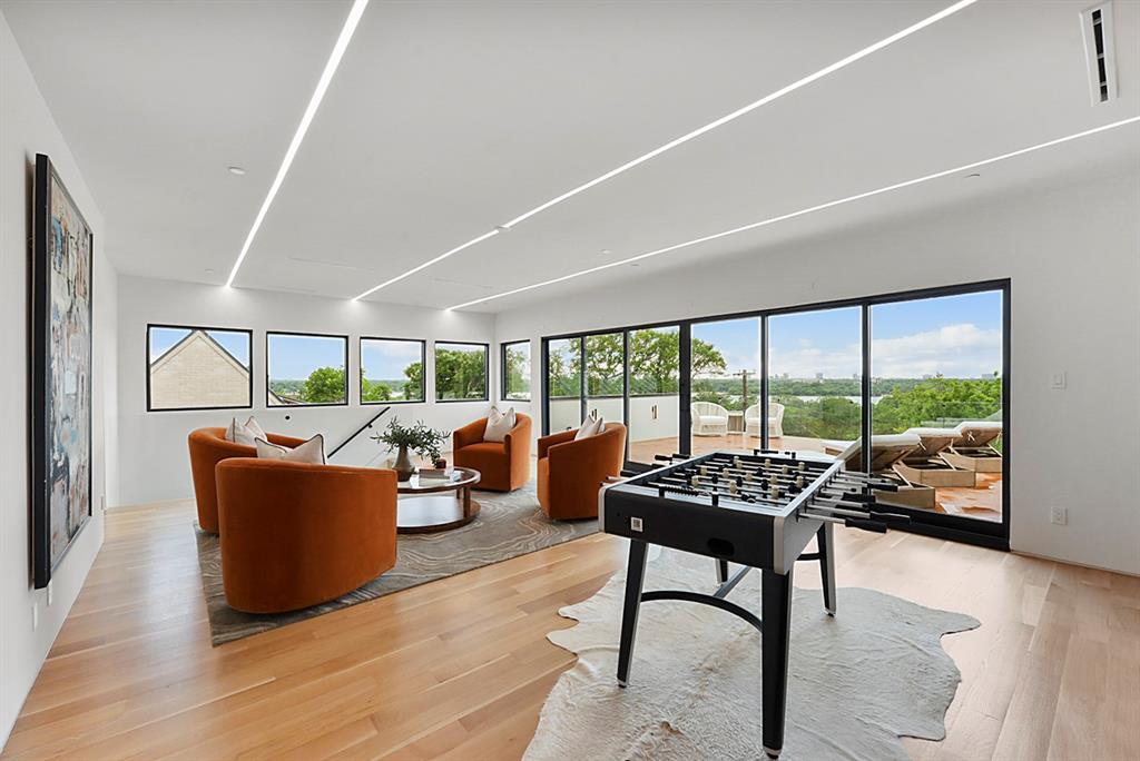 9457 Waterview Road Dallas, TX 75218 - Photo 22 of 25 Spacious entertainment room featuring recessed linear lighting, light wood-finish flooring, and expansive sliding glass doors