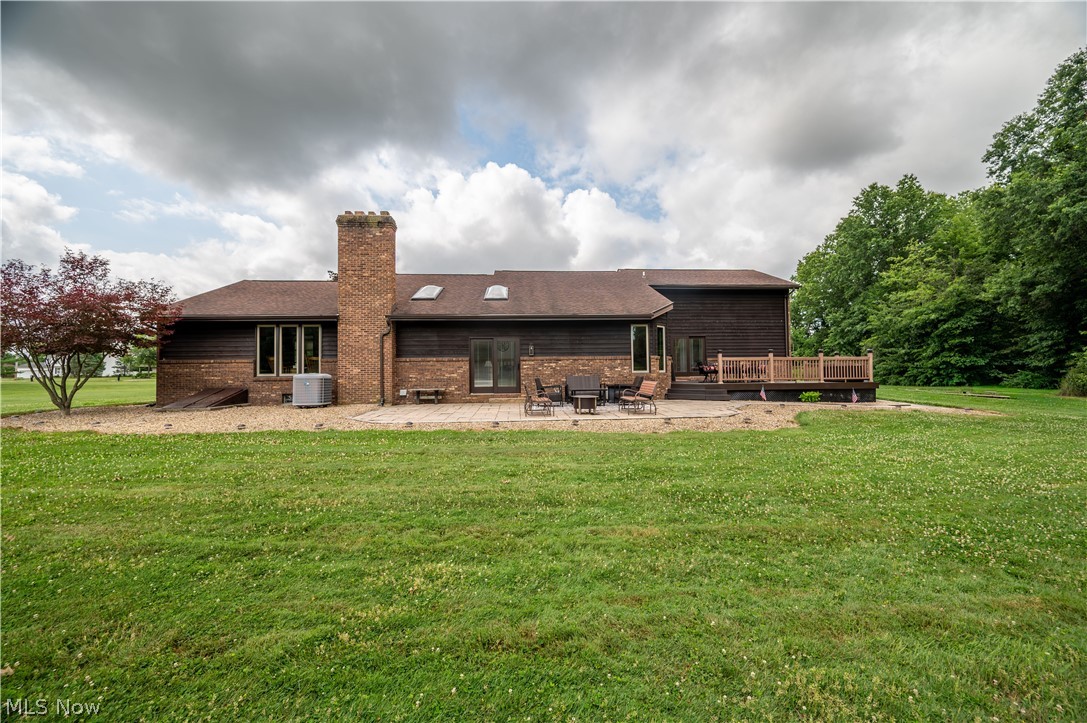 405 Airport Road Northwest Warren, OH 44481 - Photo 44 of 50 Expansive green lawn with a brown wood-sided exterior, a brick chimney, a patio area, a wood deck, and skylights