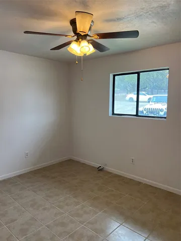 an empty room with a ceiling fan and window