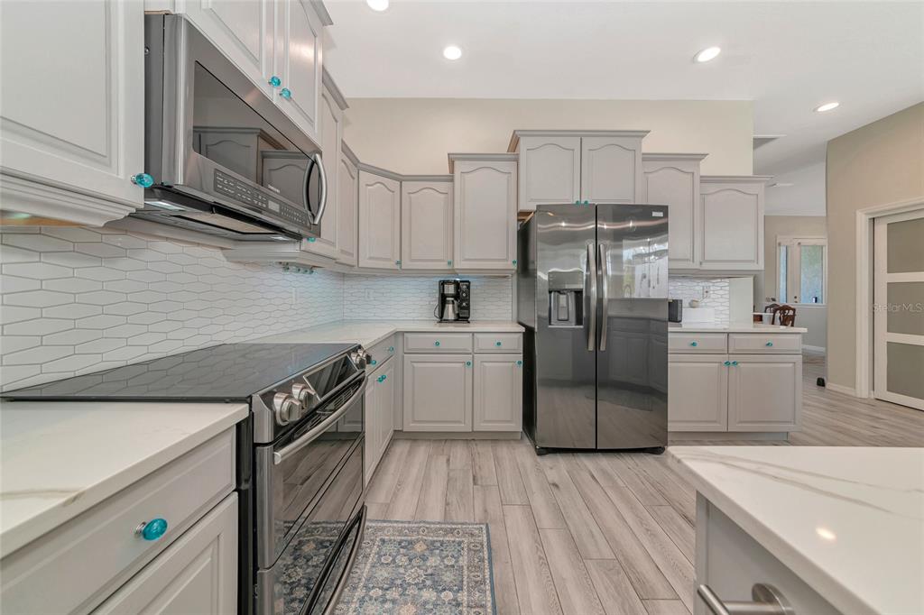 1019 Scherer Way Osprey, FL 34229 - Photo 5 of 56 a kitchen with stainless steel appliances granite countertop a refrigerator a sink dishwasher a stove and white cabinets with wooden floor