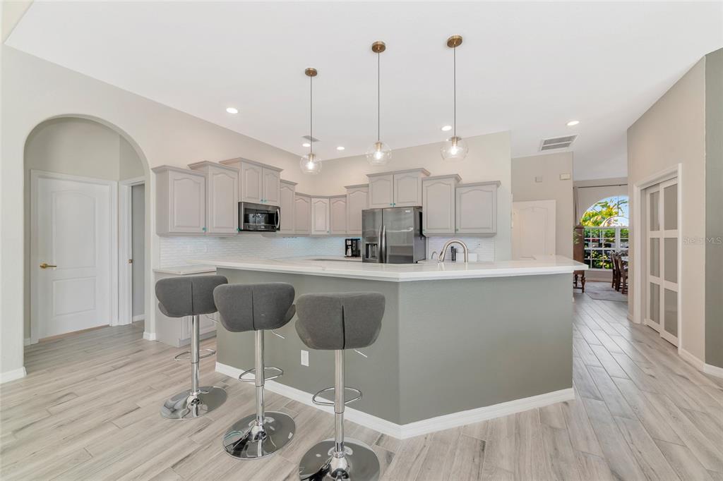 1019 Scherer Way Osprey, FL 34229 - Photo 6 of 56 a kitchen with kitchen island stainless steel appliances a dining table chairs sink and wooden floor