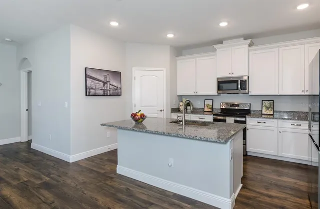 a kitchen with stainless steel appliances granite countertop a sink a stove a microwave a sink a refrigerator and cabinets