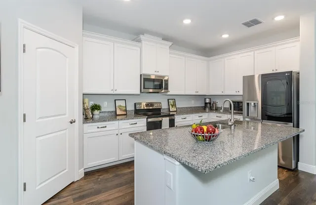 a kitchen with stainless steel appliances granite countertop a refrigerator stove microwave and sink