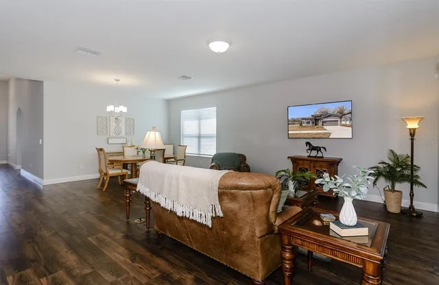 a living room with furniture and a dining table with wooden floor