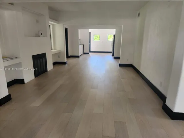 an empty room with a fireplace and wooden floor