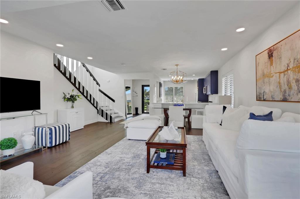 605 8th Avenue South, Unit 605 Naples, FL 34102 - Photo 11 of 50 Living room featuring wood finished floors, recessed lighting, stairway, and a chandelier