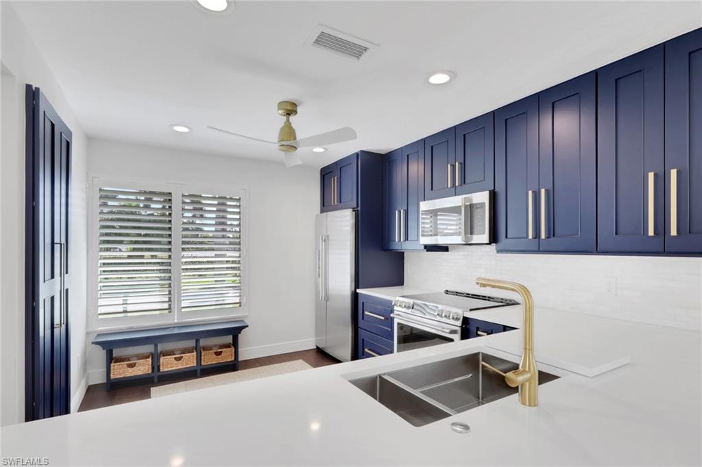 605 8th Avenue South, Unit 605 Naples, FL 34102 - Photo 7 of 50 Kitchen with blue cabinets, appliances with stainless steel finishes, recessed lighting, a ceiling fan, and backsplash