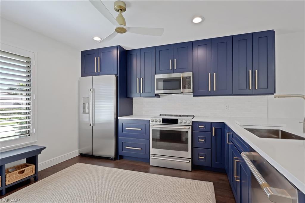 605 8th Avenue South, Unit 605 Naples, FL 34102 - Photo 8 of 50 Kitchen with blue cabinetry, stainless steel appliances, light stone counters, dark wood-style floors, and recessed lighting