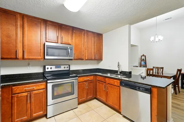 a kitchen with stainless steel appliances granite countertop a refrigerator and a stove top oven