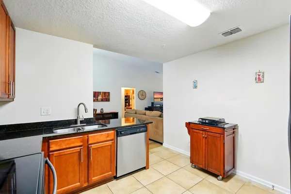a kitchen with granite countertop stainless steel appliances wooden cabinets and a sink