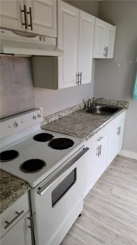 a kitchen with granite countertop a sink a stove and cabinets