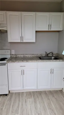a kitchen with granite countertop white cabinets and a sink