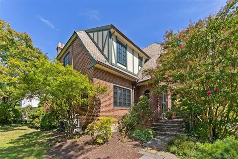 a front view of a house with plants and trees