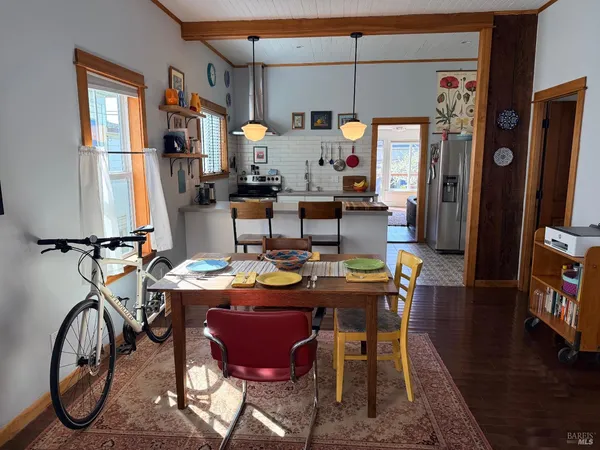 a view of a dining room with furniture one side kitchen view and wooden floor