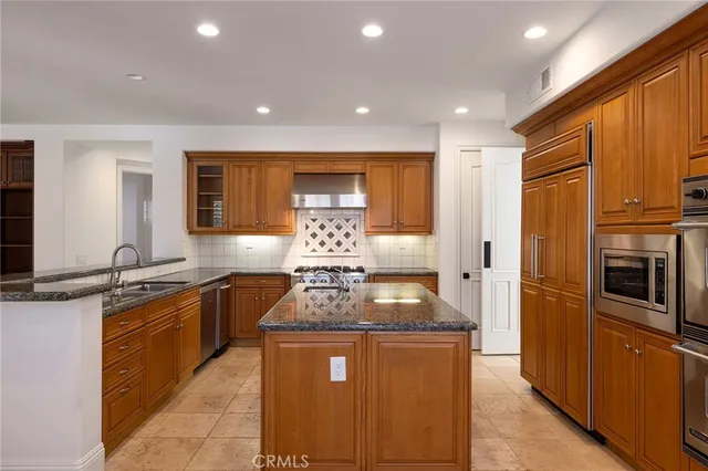 a kitchen with stainless steel appliances granite countertop a sink a stove and a refrigerator