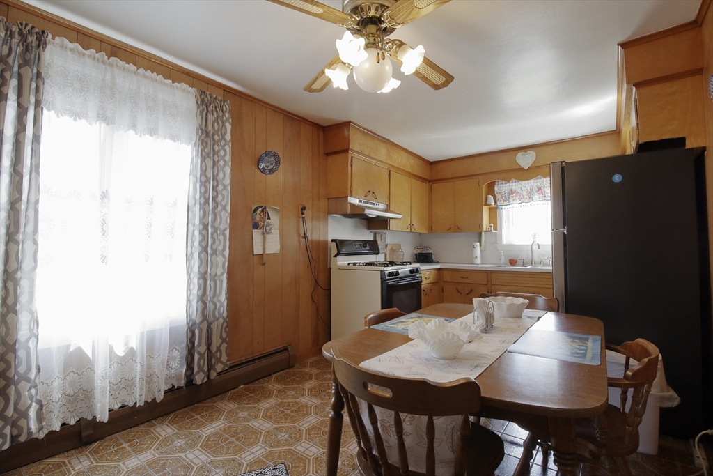 130 Massey Road Tiverton, RI 02878 - Photo 9 of 16 a kitchen with stainless steel appliances granite countertop a refrigerator a sink a stove a dining table and chairs with wooden floor