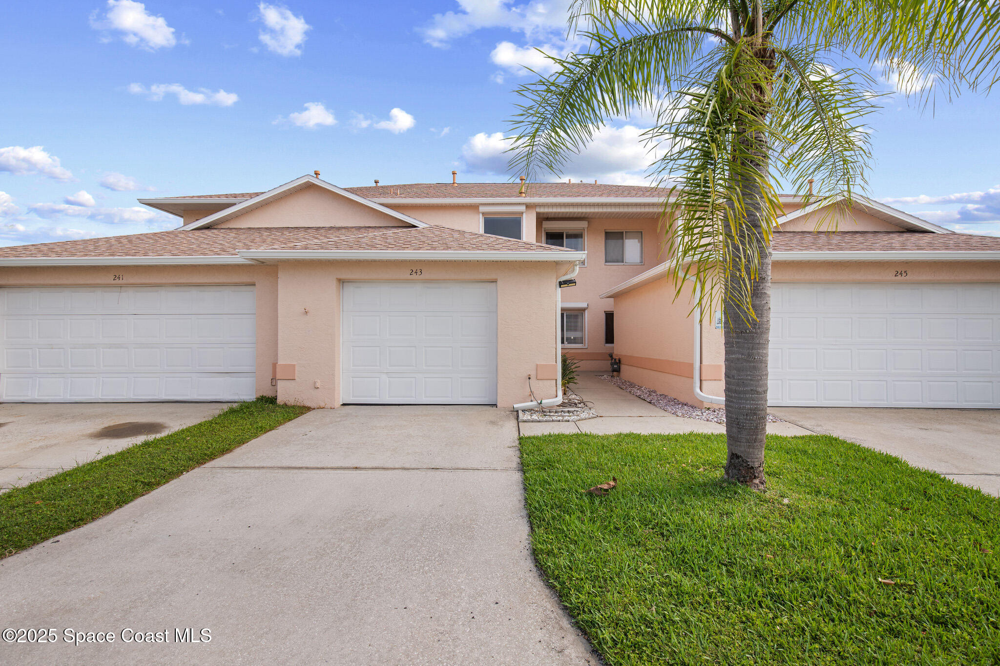 a front view of a house with a yard and palm trees