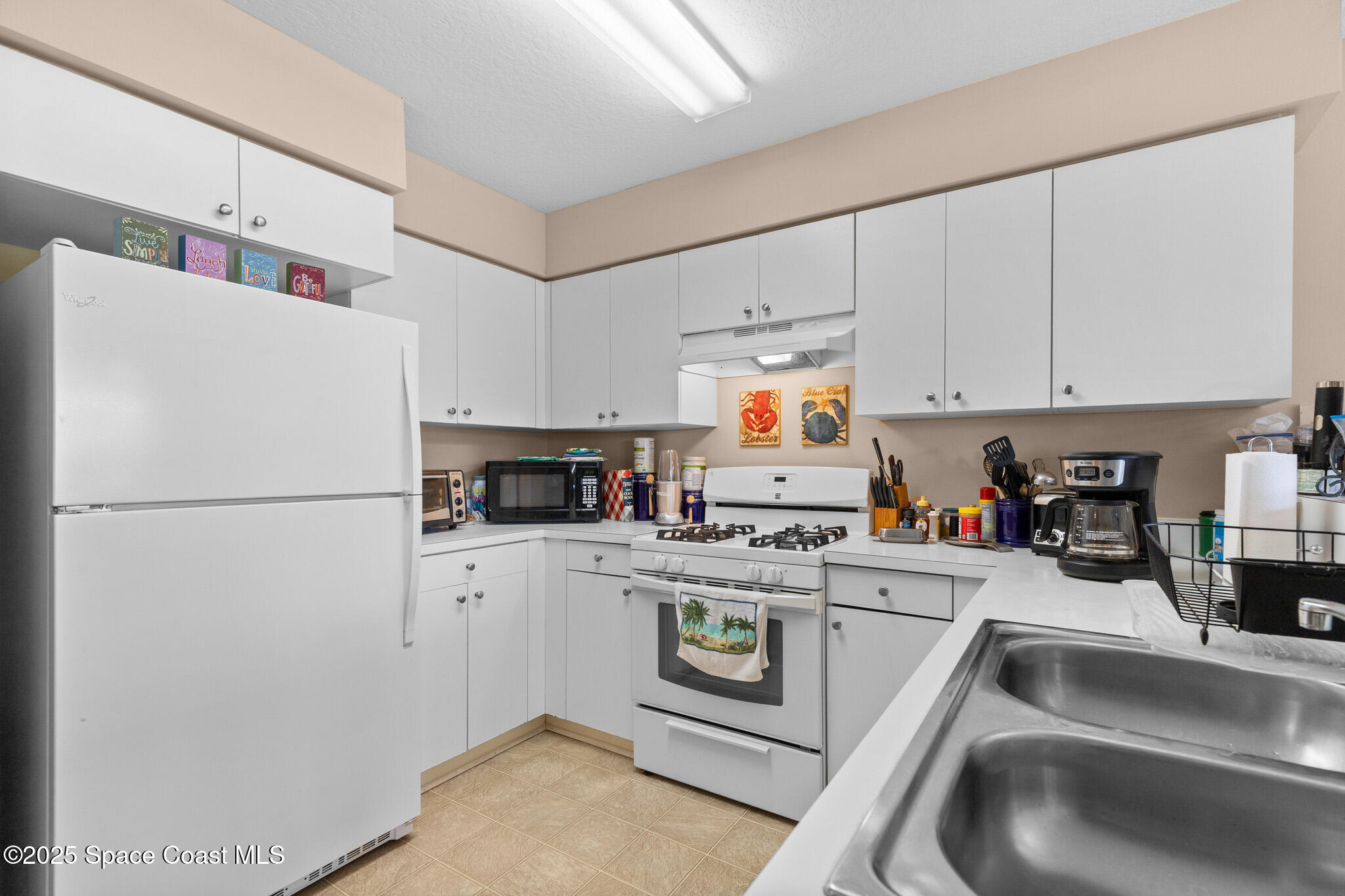 243 Forecast Lane, Unit 421 Rockledge, FL 32955 - Photo 14 of 43 a kitchen with a refrigerator a stove a sink and white cabinets