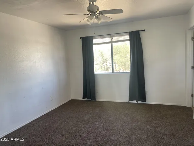 an empty room with a window and a fan