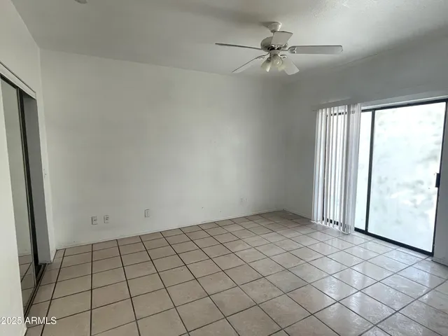 an empty room with windows and fan