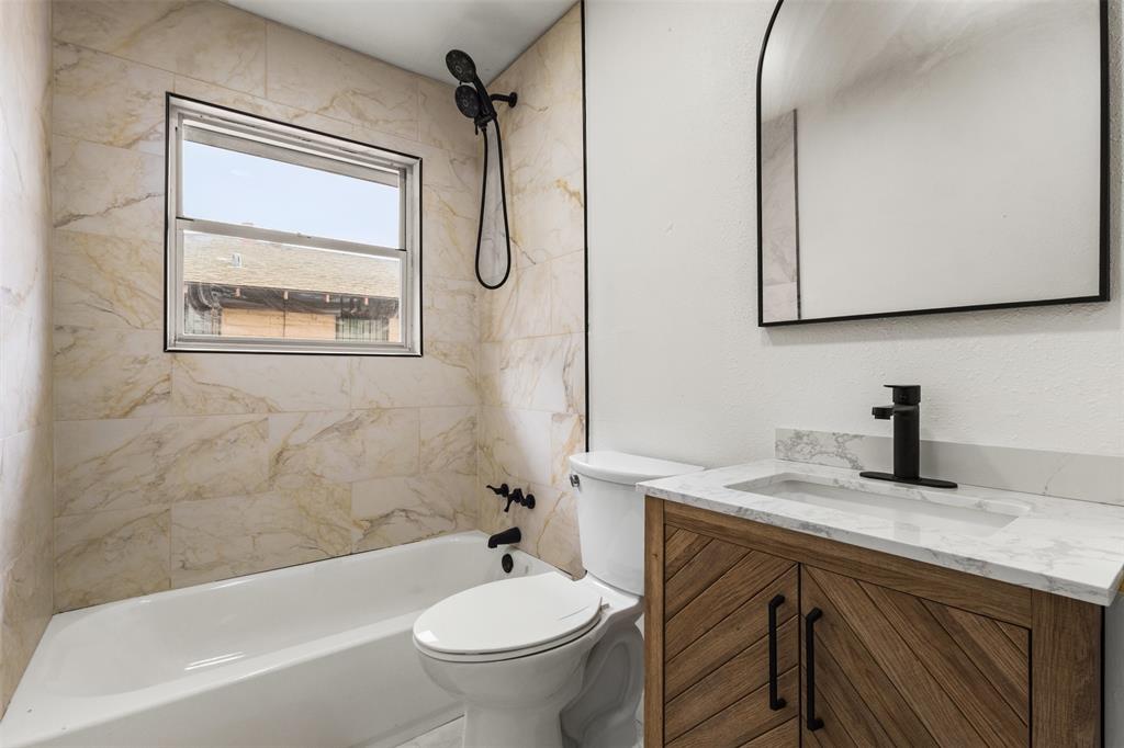 1917 South Vernon Avenue Dallas, TX 75224 - Photo 22 of 28 Bathroom featuring a tub/shower combination with marble-look tile surround and a window