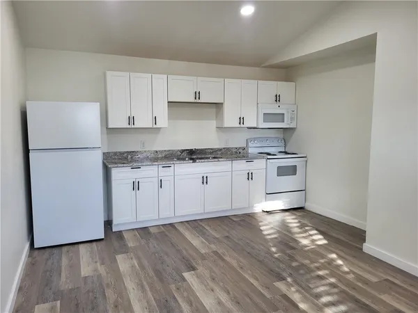a kitchen with a sink a stove a refrigerator and white cabinets