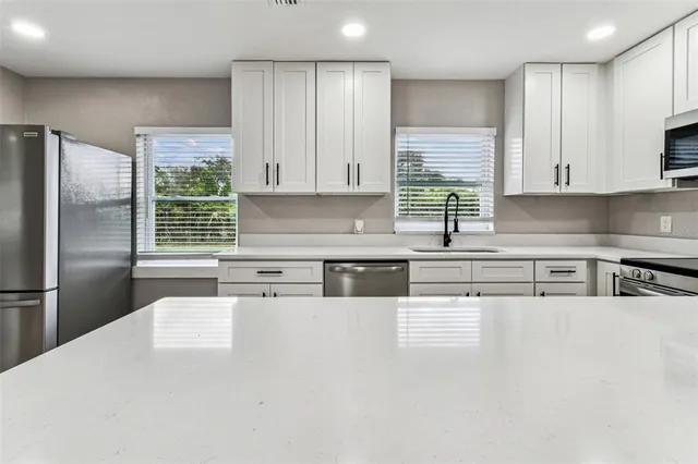 a kitchen with stainless steel appliances granite countertop a refrigerator and a sink