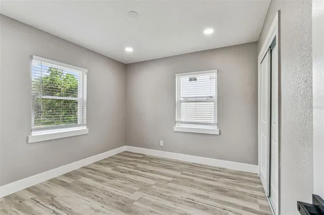 an empty room with wooden floor and windows
