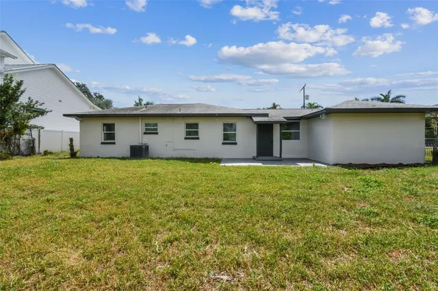 a view of a white house with a big yard plants and large trees