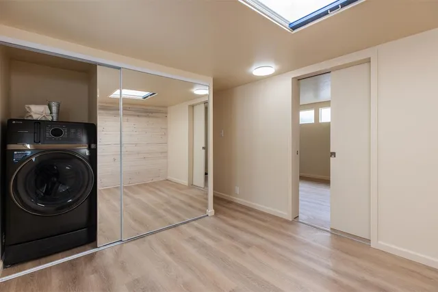 a view of an empty room with wooden floor and closet