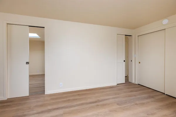 an empty room with wooden floor cabinet and windows