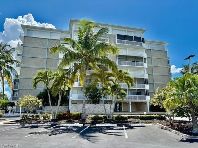 a front view of a building with glass windows and palm trees
