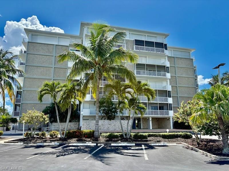 a front view of a building with glass windows and palm trees