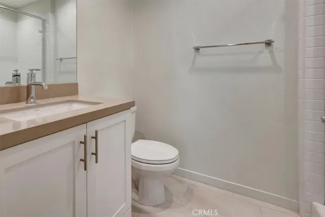 a bathroom with a granite countertop toilet and a sink