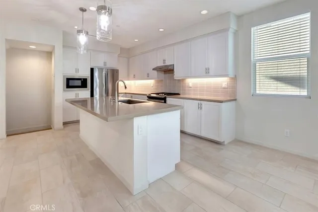 a kitchen with kitchen island a stove a sink a refrigerator and white cabinets with wooden floor