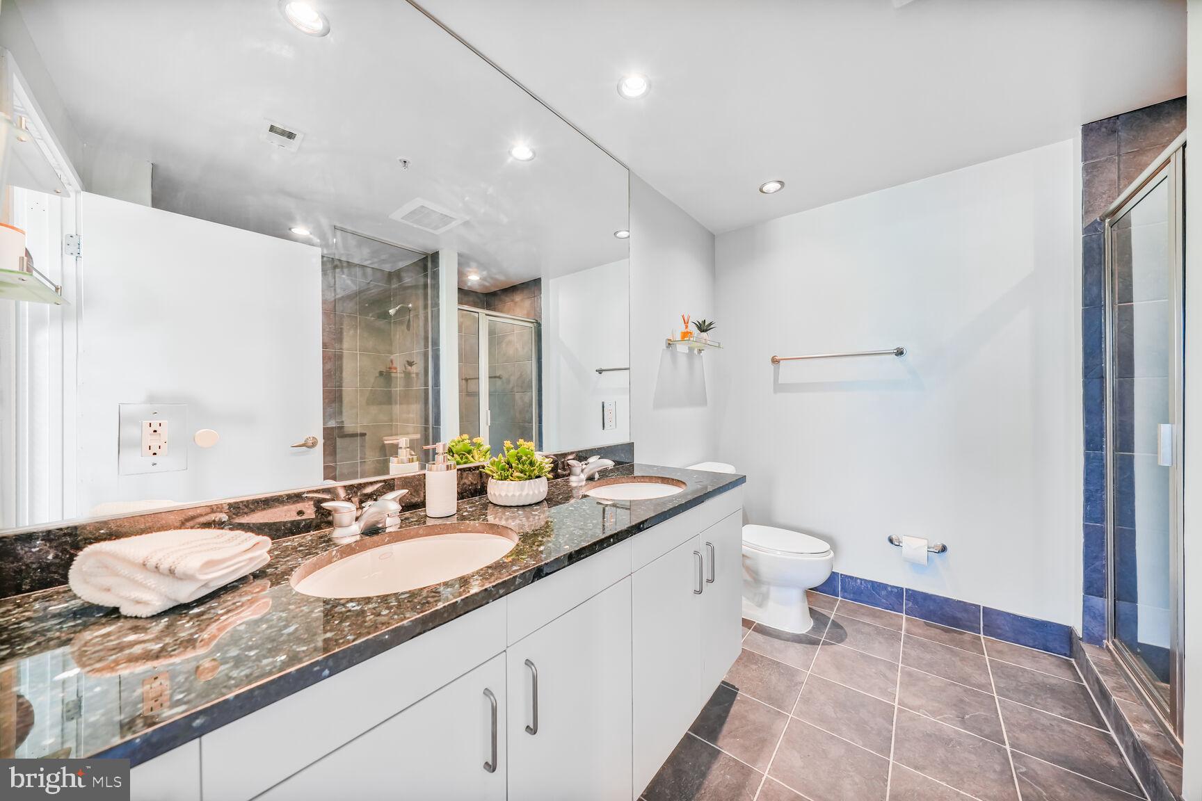 3409 Wilson Boulevard, Unit 211 Arlington, VA 22201 - Photo 11 of 30 a spacious bathroom with a granite countertop sink a toilet and a mirror