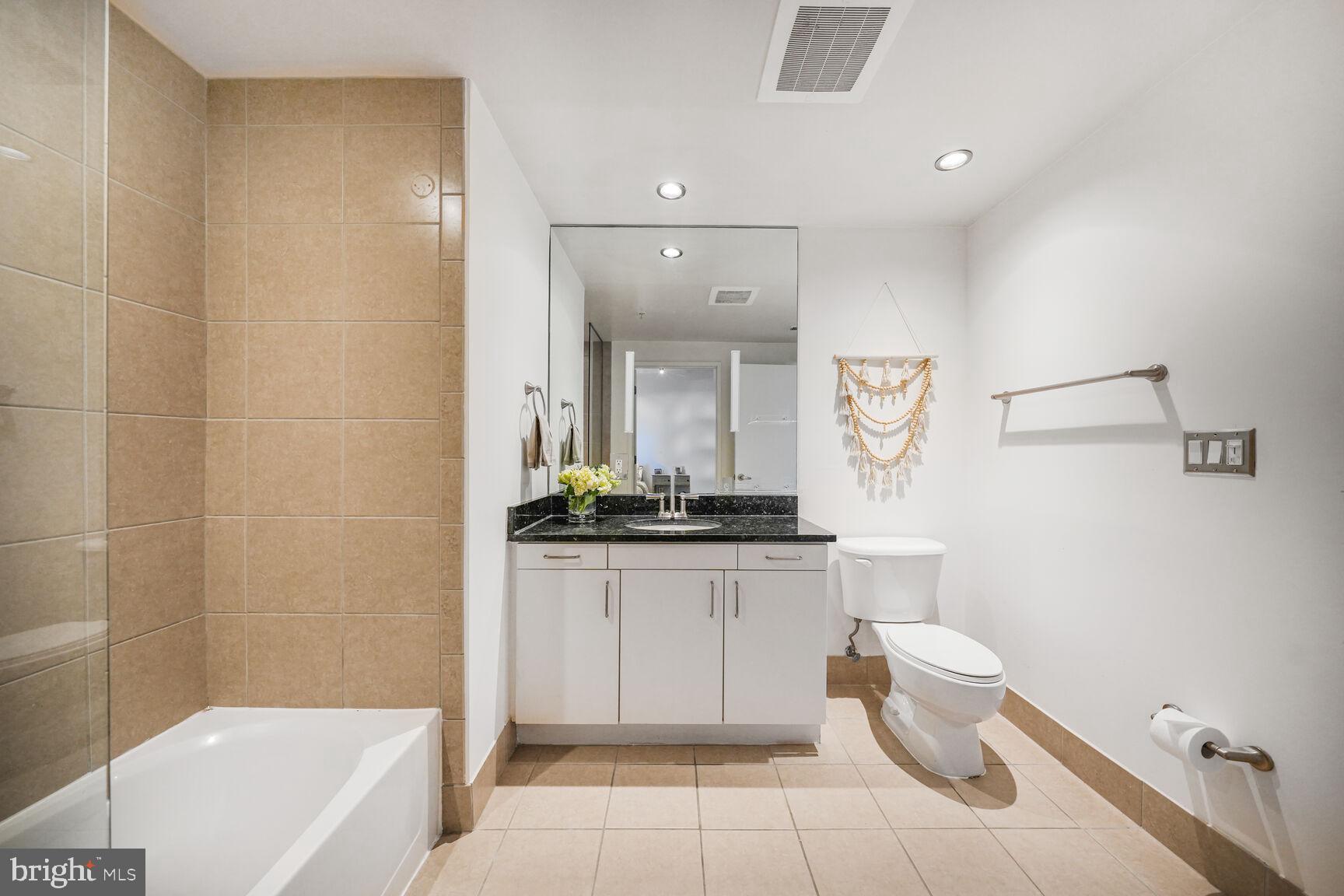 3409 Wilson Boulevard, Unit 211 Arlington, VA 22201 - Photo 17 of 30 a bathroom with a granite countertop sink a toilet and bathtub